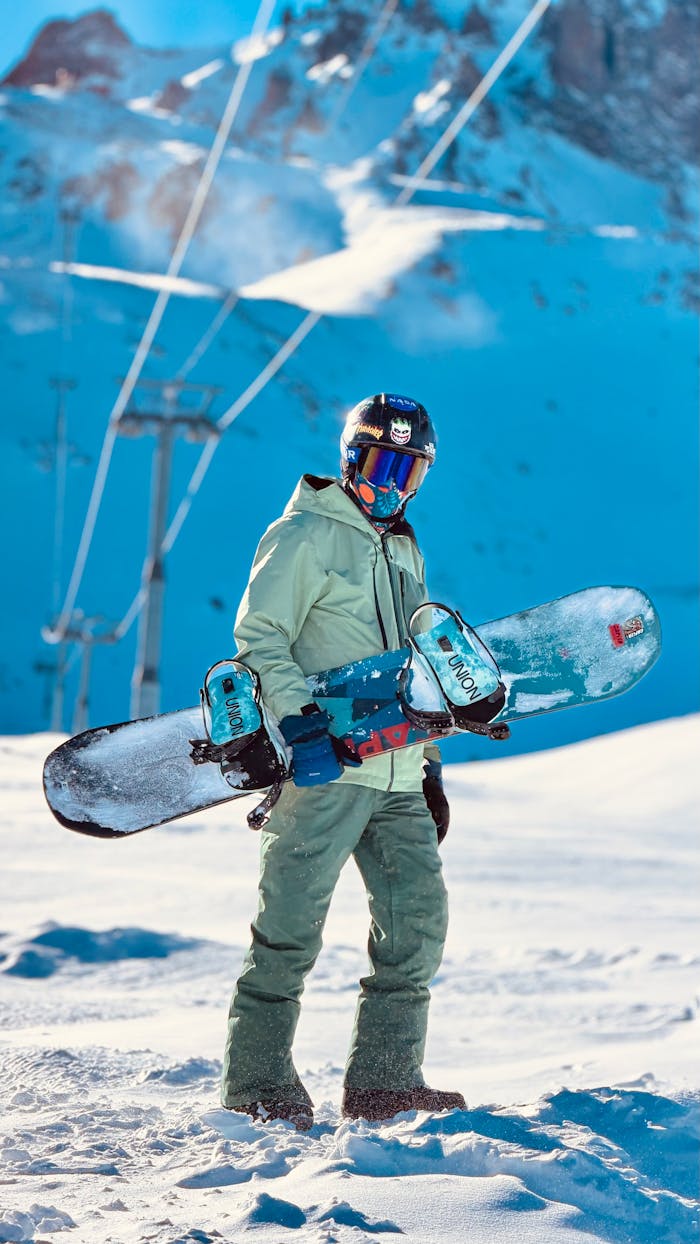 Snowboarder posing with gear on a snowy mountain slope, perfect winter adventure scene.